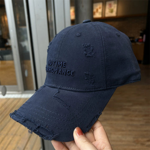 A navy blue cotton baseball cap with distressed brim and embroidered text, adjustable back strap.