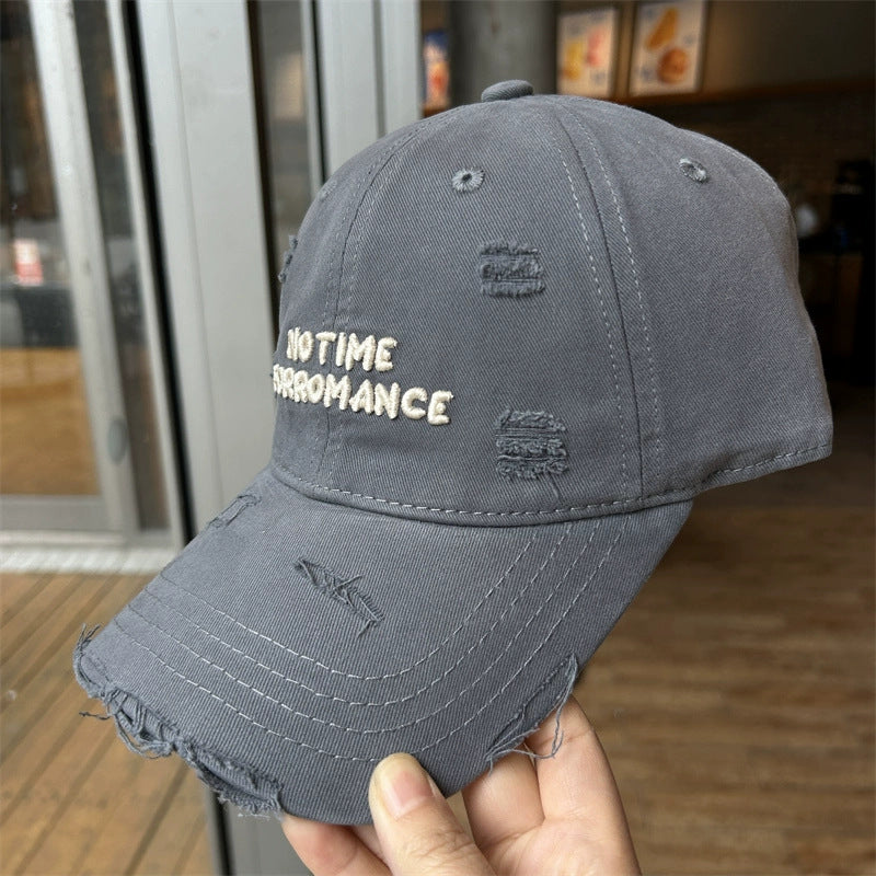 Distressed grey cotton baseball cap with embroidered lettering and frayed edges, adjustable strap.